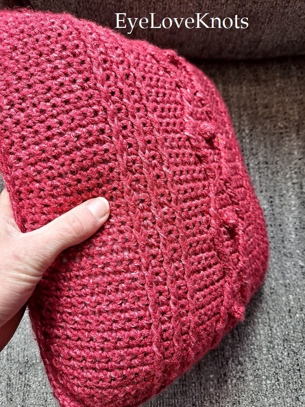 Side view of cabled crochet throw pillow on sofa