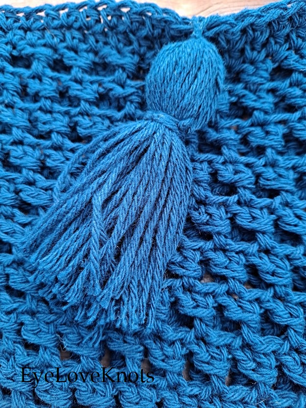 Close up of blue cotton tassel from crocheted bucket bag beauty