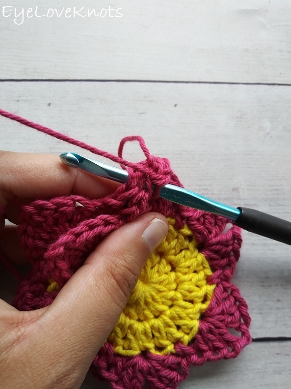 close up of how to crochet through two layers of pink and yellow flowers, EyeLoveKnots