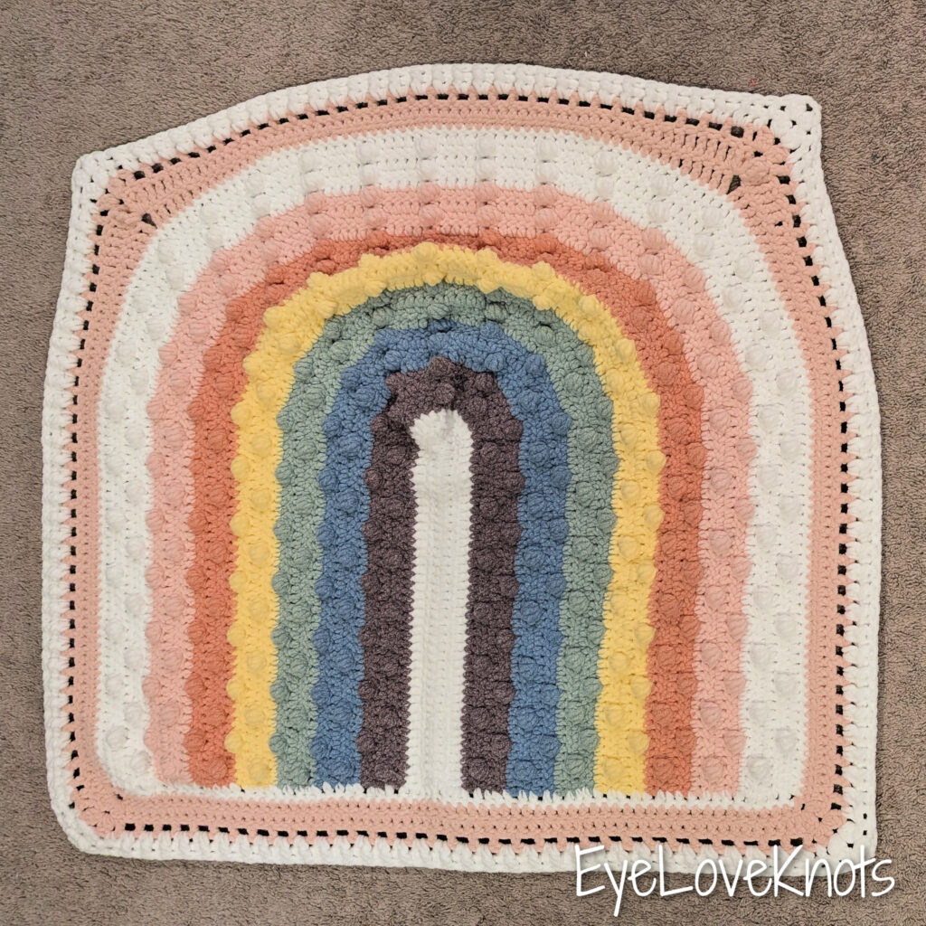 This is a crochet pattern review of the Juni Bobble Rainbow Blanket designed by Mama Made Minis. Review done by Candace of T&C Crafters for EyeLoveKnots.