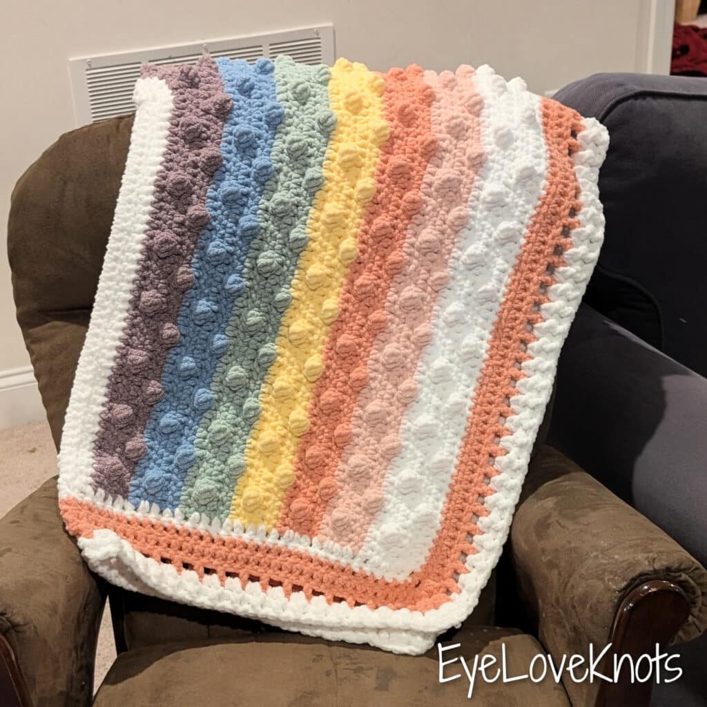 This is a crochet pattern review of the Juni Bobble Rainbow Blanket designed by Mama Made Minis. Review done by Candace of T&C Crafters for EyeLoveKnots.
