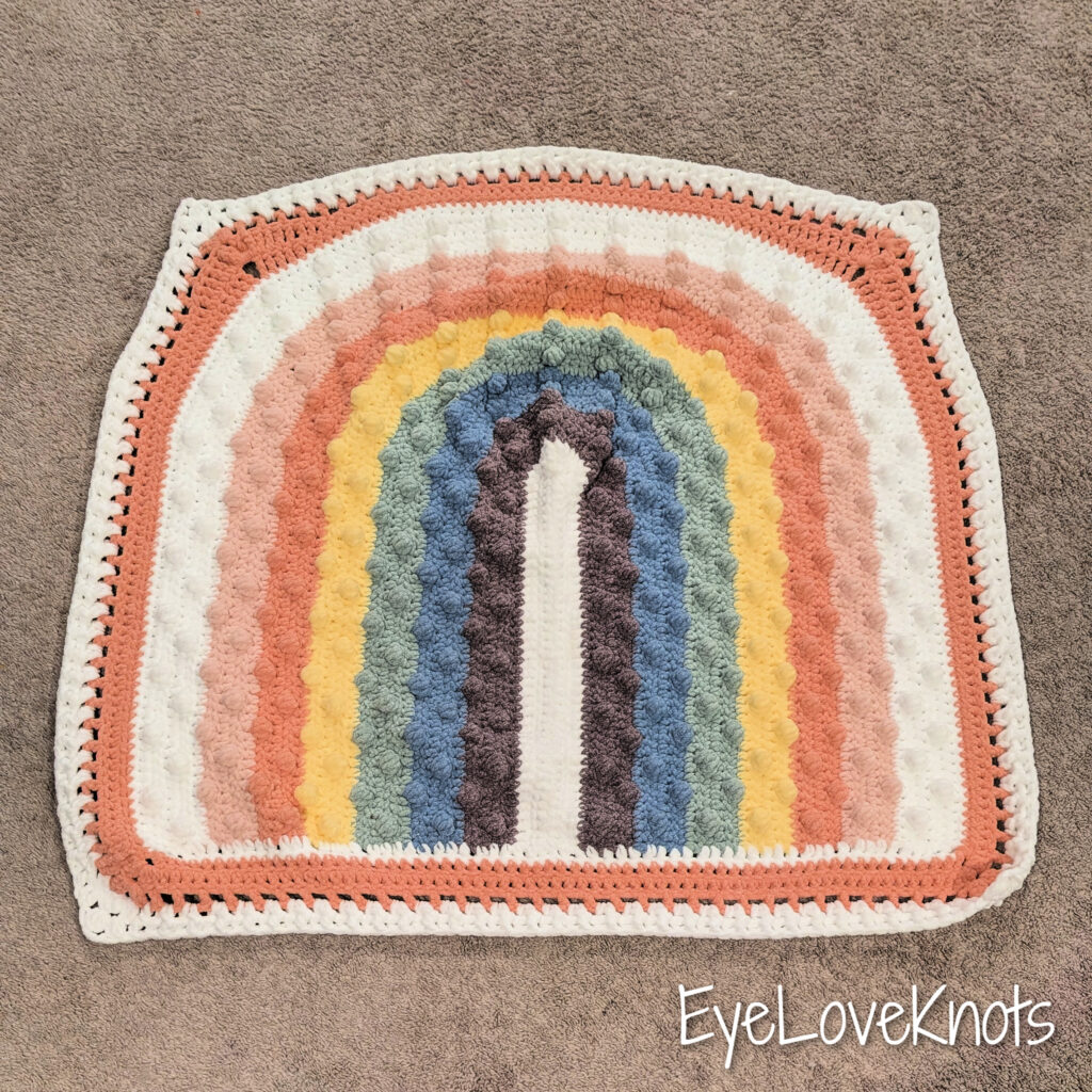 This is a crochet pattern review of the Juni Bobble Rainbow Blanket designed by Mama Made Minis. Review done by Candace of T&C Crafters for EyeLoveKnots.